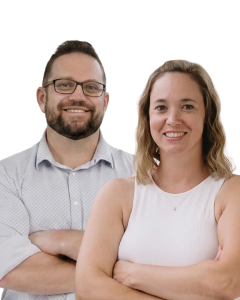Portrait of Mike and Kayla Mann standing together, arms folded, smiling